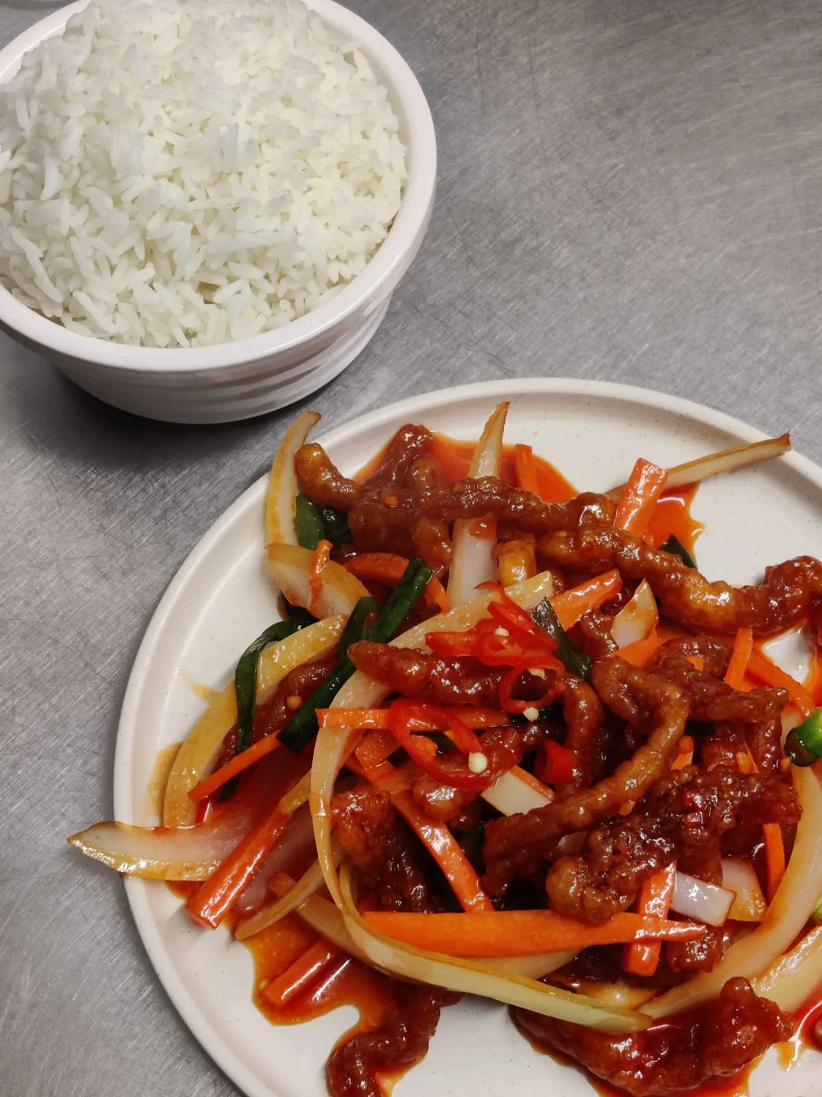 Shredded crispy beef tossed with onion, carrot and red chilli, with a pot of boiled rice