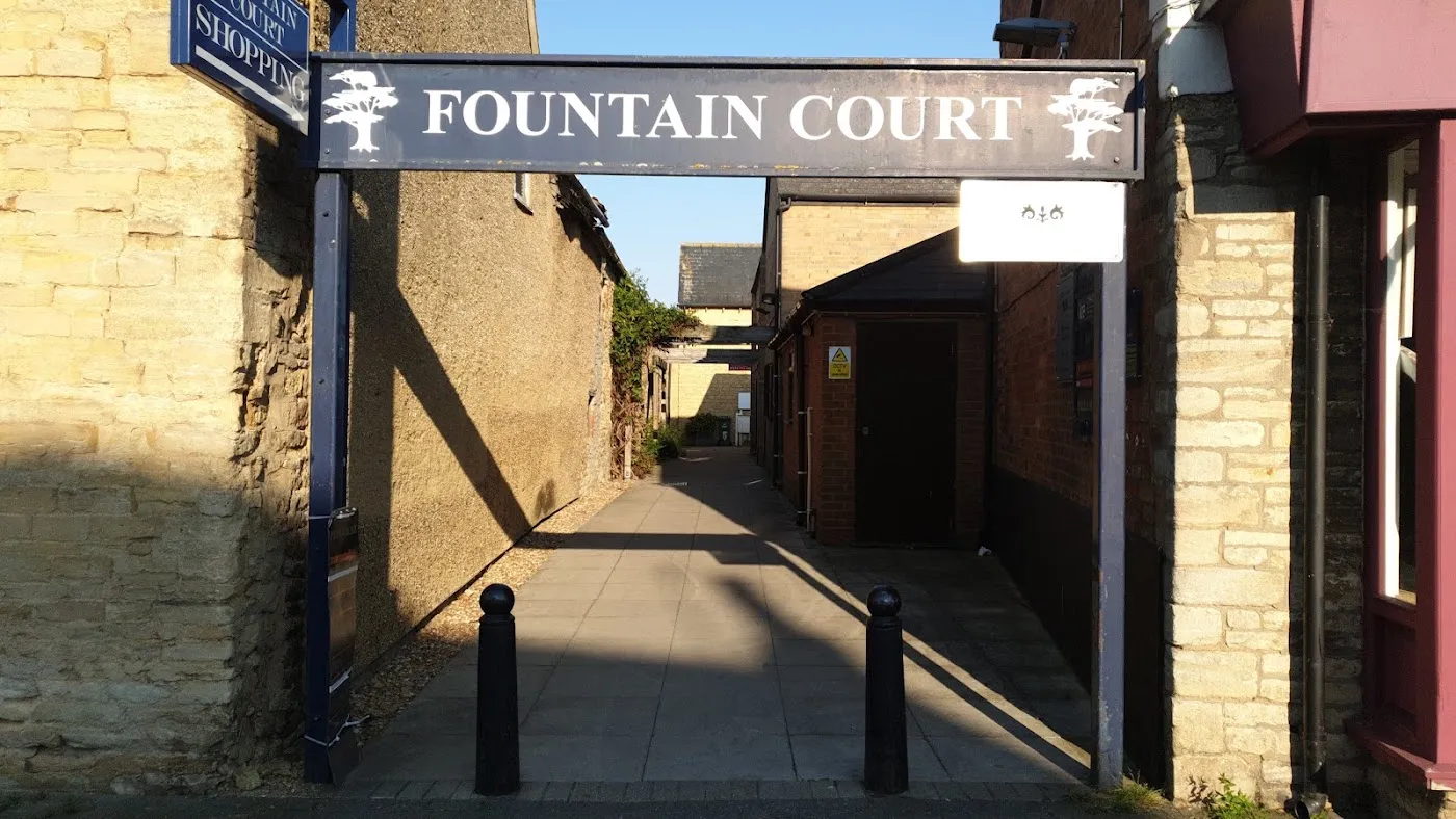 The navy Fountain Court arch sign over the paved passage off Olney High Street