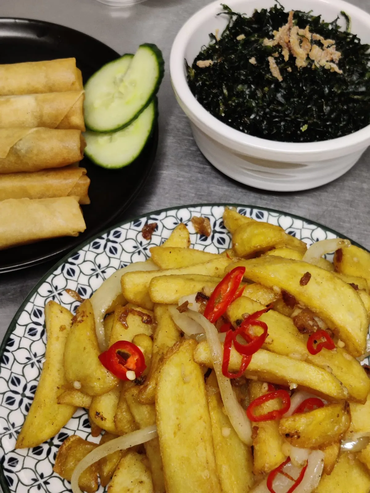 Spring rolls with cucumber, a pot of crispy seaweed, and chips tossed with chilli and onion